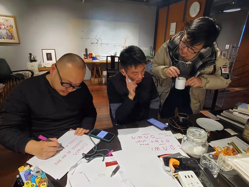 刘毅(左一)陈豪(右一)在工作室构思DAWA标识的设计方案 刘毅(左一)陈豪(右一)在工作室构思DAWA标识的设计方案